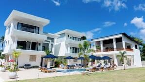 A modern two-story house with a swimming pool, lounge chairs, and umbrellas. - Luxury Villa for 10 Guests with Pool and Jacuzzi (Las Terrenas)