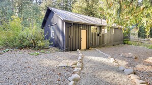 A rustic cabin with a metal roof, surrounded by dense forest. - Mt Hood Launchpad! Cozy Retro Rhododendron Cabin (Rhododendron)