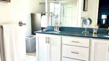 Un baño moderno con un espejo grande, lavamanos dobles y un mueble de tocador con cajones.