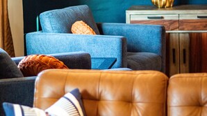 A living room with a blue sofa, a brown leather couch, and a wooden cabinet.