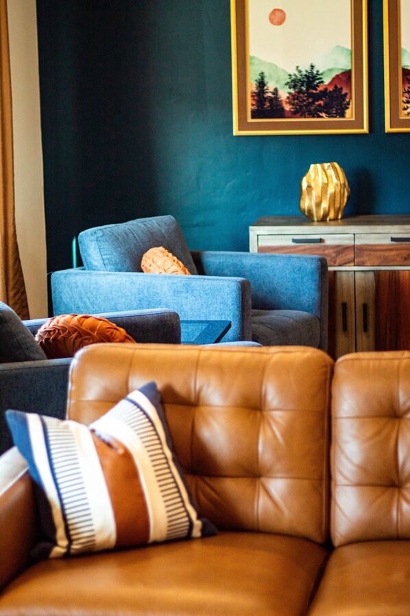 A living room with a blue sofa, a brown leather couch, and a wooden cabinet.