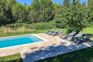 Ein Schwimmbecken mit gefliestem Sonnendeck und arrangierten Liegestühlen.