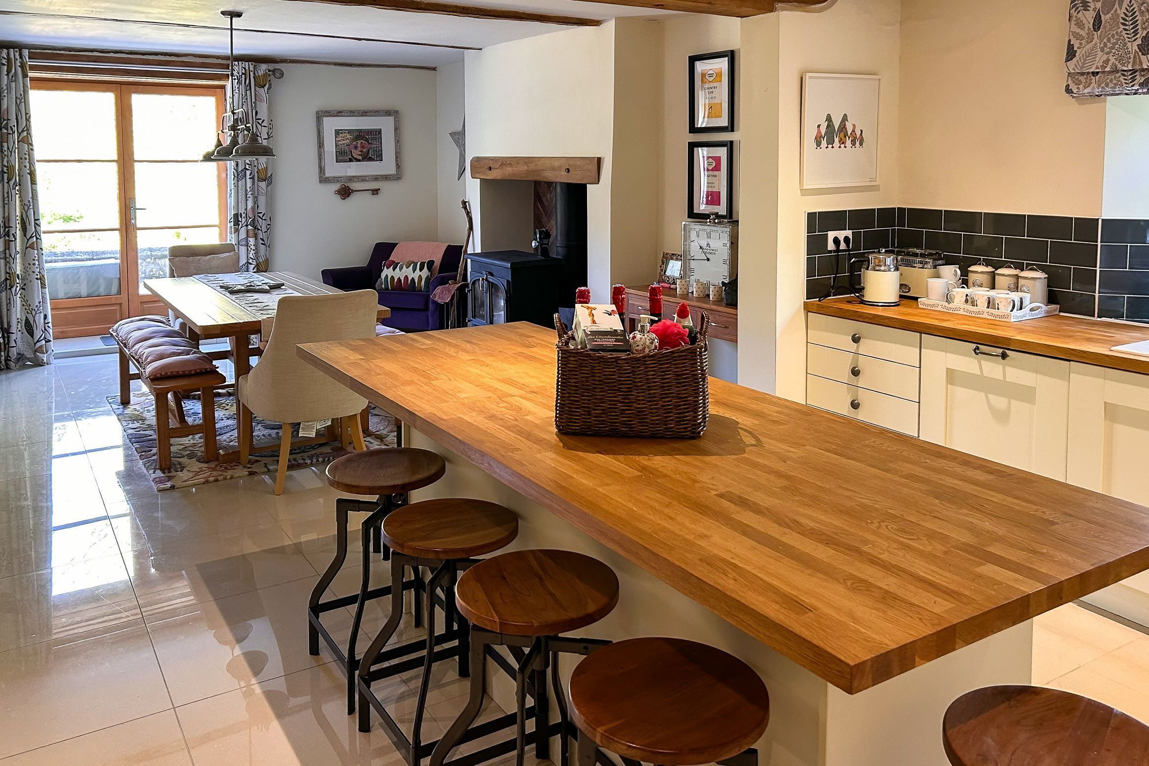 A modern kitchen with a wooden countertop, bar stools, and a built-in stove.