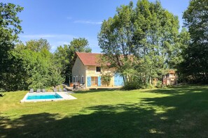A two-story stone house with a swimming pool, surrounded by lush greenery and trees. - La Grange Des Epinettes (Teyjat)
