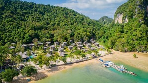 An aerial view of a resort with multiple bungalow-style accommodations, a beach, and boats docked near the shore. - TreeHouse Villas - Hilltop Pool Villa (Ko Yao Noi)