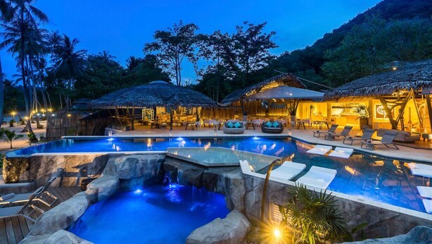 A resort pool area with lounge chairs and thatched-roof structures. - TreeHouse Villas - Hilltop Pool Villa (Ko Yao Noi)
