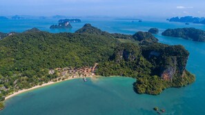An aerial view of a coastal area with a beach, dense forest, and scattered islands. - TreeHouse Villas - Beachfront Pool Villa (Ko Yao Noi)