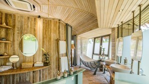 A modern bathroom with a wooden wall, a large mirror, a bathtub, and a sink. - TreeHouse Villas - TreeHouse Villa (Ko Yao Noi)