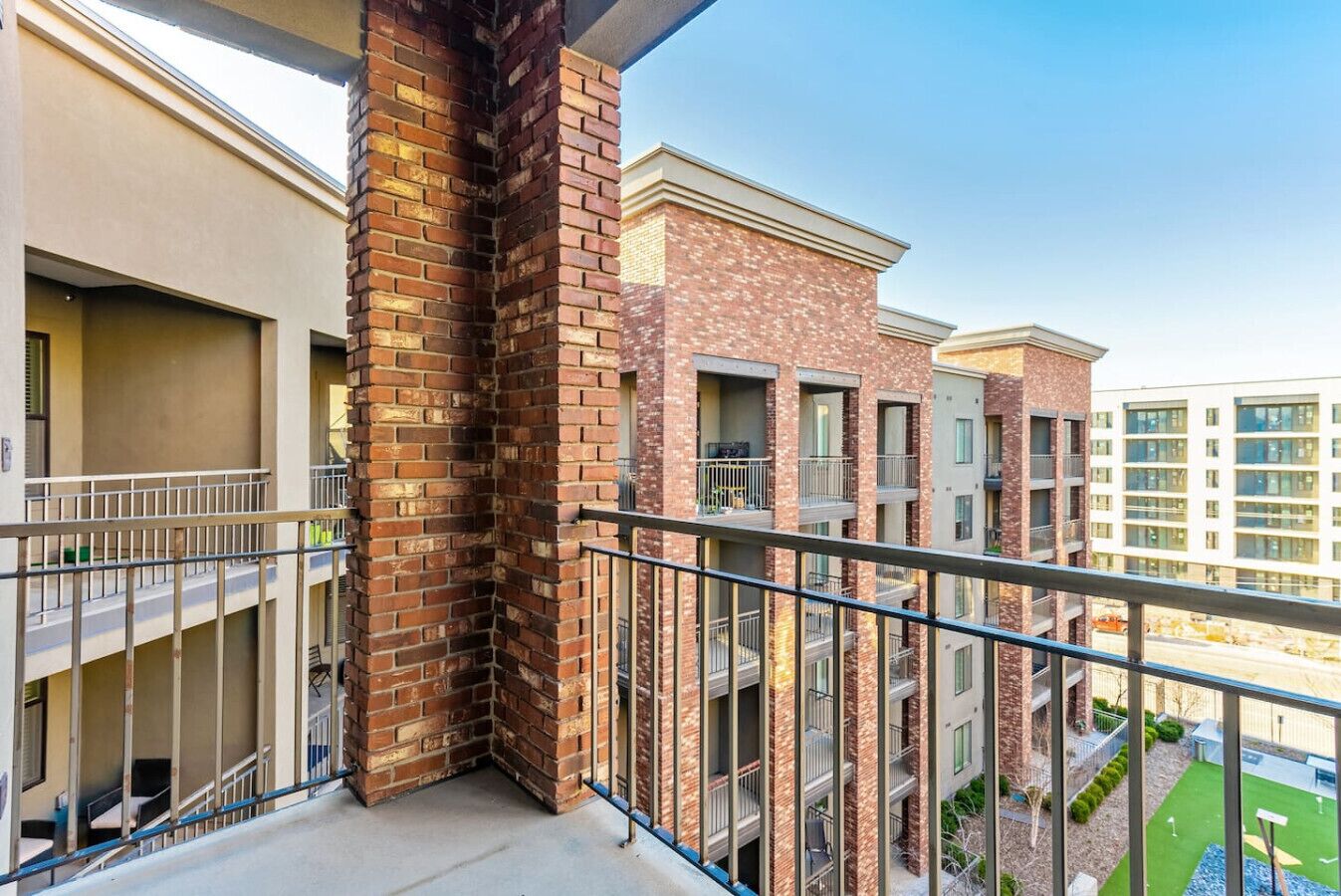 Una esquina de edificio residencial con chimenea de ladrillo, balcones y vista a edificios vecinos.