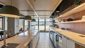 Cocina moderna con una encimera larga, iluminación colgante y vistas a la ciudad.