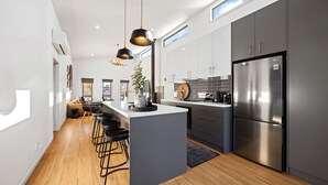 A modern kitchen with a central island, stainless steel appliances, and a bar area with stools.