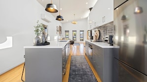 A modern kitchen with a central island, stainless steel appliances, and pendant lighting.