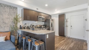 Una cocina moderna con una isla central, taburetes de bar y microondas integrado.