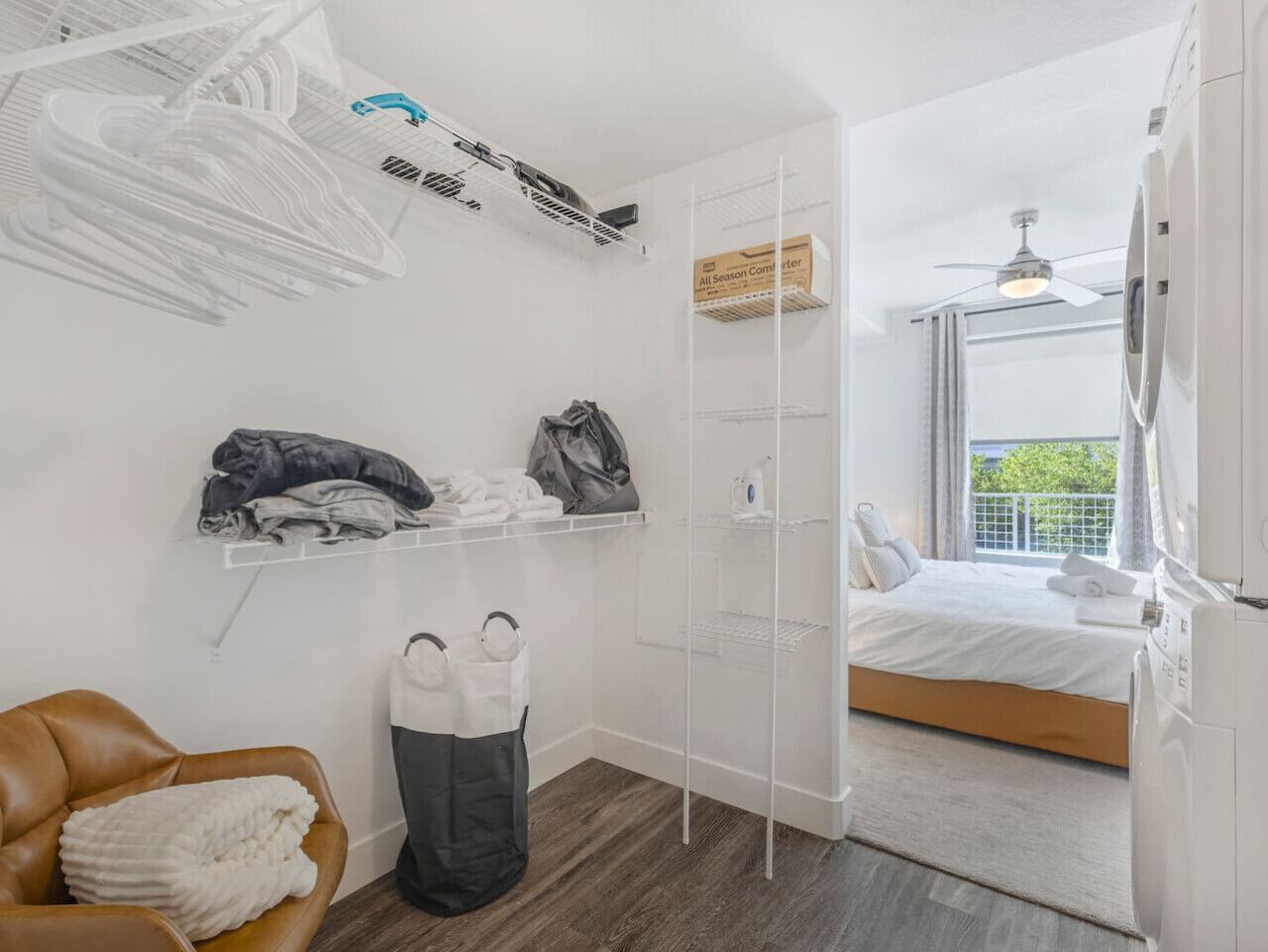 Quarto de hotel compacto com cama, área de estar com uma cadeira, guarda-roupa e varanda com vista.