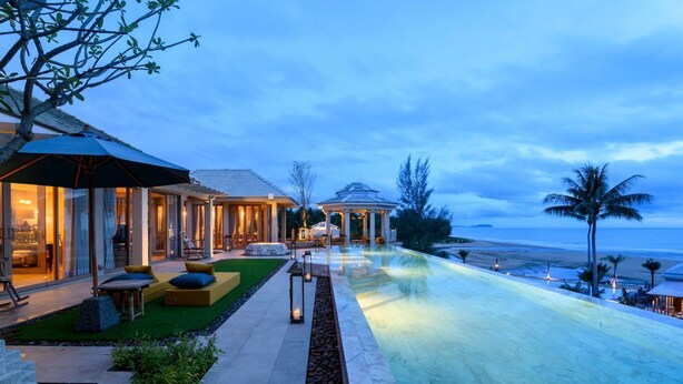 A resort with a infinity pool, outdoor seating, and a view of the beach.