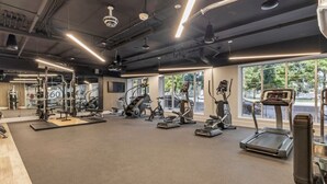 A gym with various exercise equipment, large windows, and a modern design.