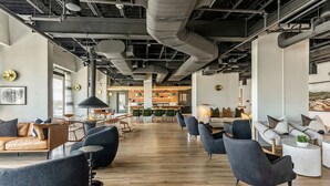 A spacious open-plan office with modern furniture, exposed ductwork, and a mix of seating areas.
