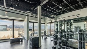 A gym with large windows, weightlifting equipment, and a view of mountains.
