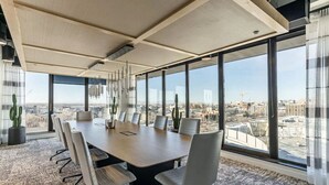 A conference room with a large table, chairs, and a city view through large windows.