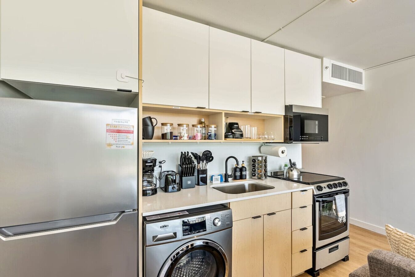Une cuisine compacte équipée d’un réfrigérateur, d’un four à micro-ondes, d’une cuisinière, d’un évier et d’un lave-linge.