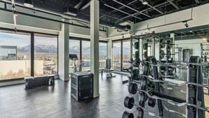 A gym with large windows, weightlifting equipment, and a view of mountains.