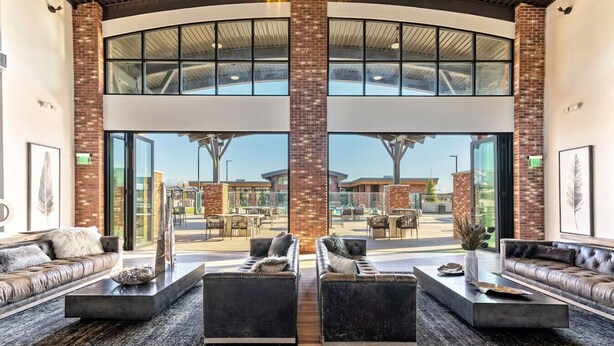A spacious lobby with leather sofas, a coffee table, and a view of the outdoor patio area.