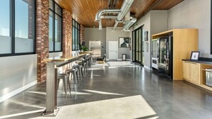 A spacious, modern kitchen with a long counter, bar stools, and a brick accent wall.