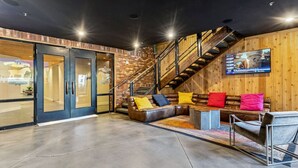 A modern interior with a leather sofa, a staircase, and a large TV on the wall.