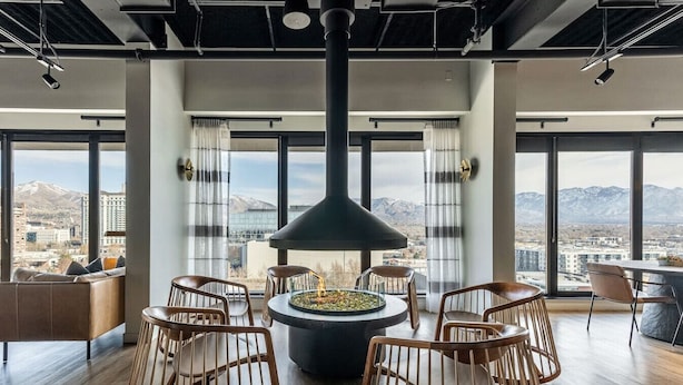 A modern interior with a central fire feature, large windows, and a view of a cityscape.