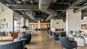A modern interior with a long corridor, seating areas, and a kitchen in the background.