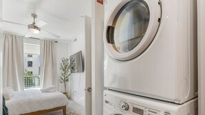 Un dormitorio con cama, lavadora y ventilador de techo.