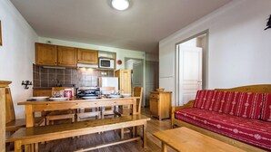 A compact living space with a kitchen, dining area, and a red patterned sofa. - Apartment for 6 to 8 people in Albiez (Albiez-Montrond)