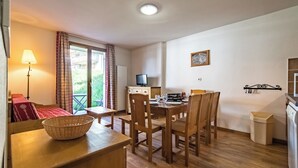A compact room with a dining table, chairs, a television, and a window with curtains. - Apartment for 6 to 8 people in Albiez (Albiez-Montrond)
