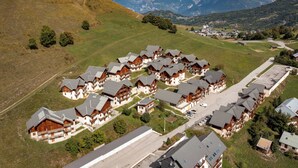 A cluster of chalet-style buildings with balconies, set against a backdrop of mountains and a clear sky. - Apartment for 6 to 8 people in Albiez (Albiez-Montrond)