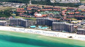 An aerial view of a coastal resort with multiple high-rise buildings, a beach, and a marina. - 2BR Golf Retreat, Sleeps 8 Comfortably (Panama City Beach)