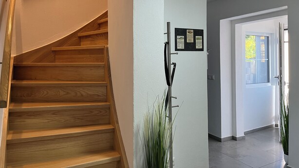Een houten trap die uitkomt op een plateau met een bord aan de muur.