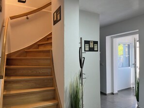 Un escalier en bois menant à un palier où est fixée une enseigne au mur.