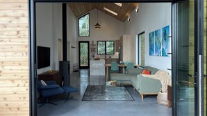A modern interior with a living area, kitchen, and dining space. - Cliffside Hideaway: Luxurious, Peaceful, with Gorgeous views Over the Ocean (Port Renfrew)