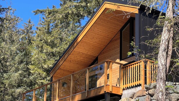 A wooden cabin with a balcony, built on a rocky hillside with trees around. - Cliffside Hideaway: Luxurious, Peaceful, with Gorgeous views Over the Ocean (Port Renfrew)