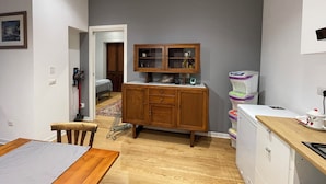 A compact kitchen with wooden cabinets, a built-in microwave, and a small dining area with a table and chairs. - Pisu Apartments (appart.Orsolina)  (Quartucciu)