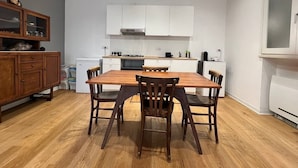 A compact kitchen with white cabinets, a wooden dining table, and a built-in oven. - Pisu Apartments (appart.Orsolina)  (Quartucciu)