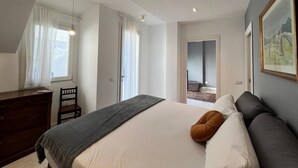 A bedroom with a bed, a dresser, a chair, and a painting on the wall. - Pisu Apartments (appart.Luigino)  (Quartucciu)