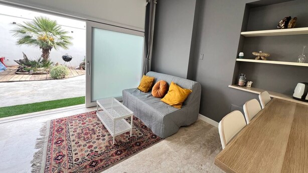A modern living room with a grey sofa, yellow cushions, a white coffee table, and a wooden dining table. - Pisu Apartments (appart.Luigino)  (Quartucciu)