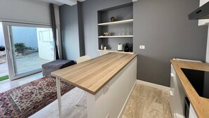 A modern kitchen with a wooden countertop, grey walls, and a built-in oven. - Pisu Apartments (appart.Luigino)  (Quartucciu)