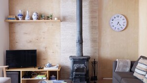 A living room with a fireplace, a television, a sofa, and a clock on the wall.