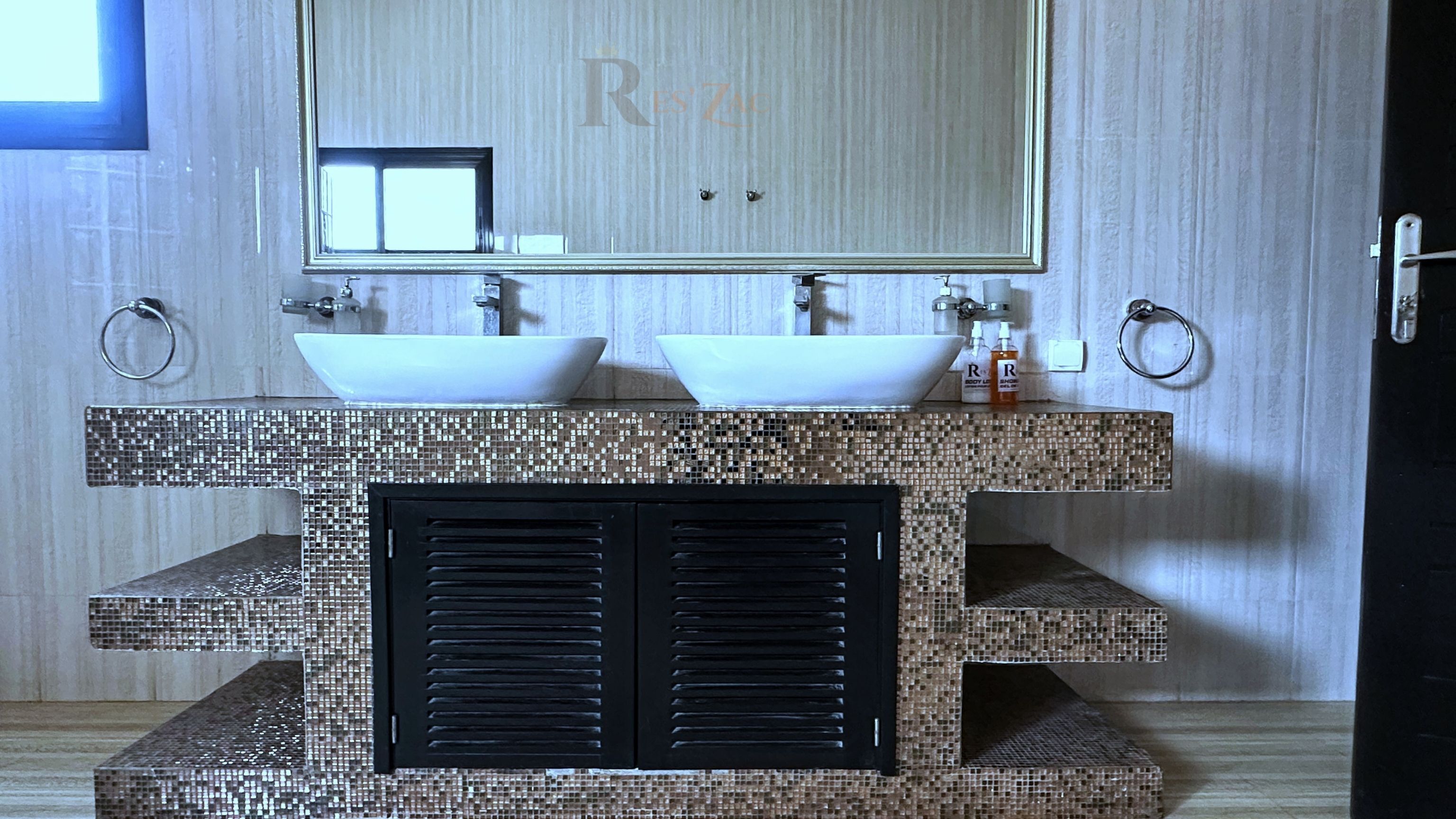 A bathroom with two sinks, a large mirror, and a decorative tiled backsplash.