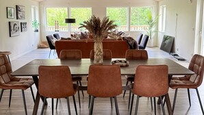 A dining area with a large wooden table, six brown upholstered chairs, and a vase with dried plants. - 4 bedroom nice home in äspered (äspered)
