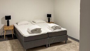 A neatly made bed with white linens and two bedside lamps on wooden nightstands. - 4 bedroom nice home in äspered (äspered)