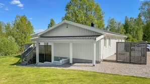 A single-story building with a covered porch, a staircase leading to a fenced entrance, and a gravel driveway. - 4 bedroom nice home in äspered (äspered)