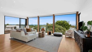 A spacious living room with a large window, a sofa, a coffee table, and a TV on a wooden cabinet.